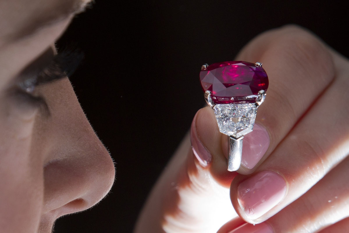 An employee of Sotheby's auction house poses with The Sunrise Ruby, a rare Burmese ruby weighing 25.59 carats and estimated to sell for $12-18 million, during a press preview in London on April 8, 2015. The gemstone will be at auction in Geneva in May 201