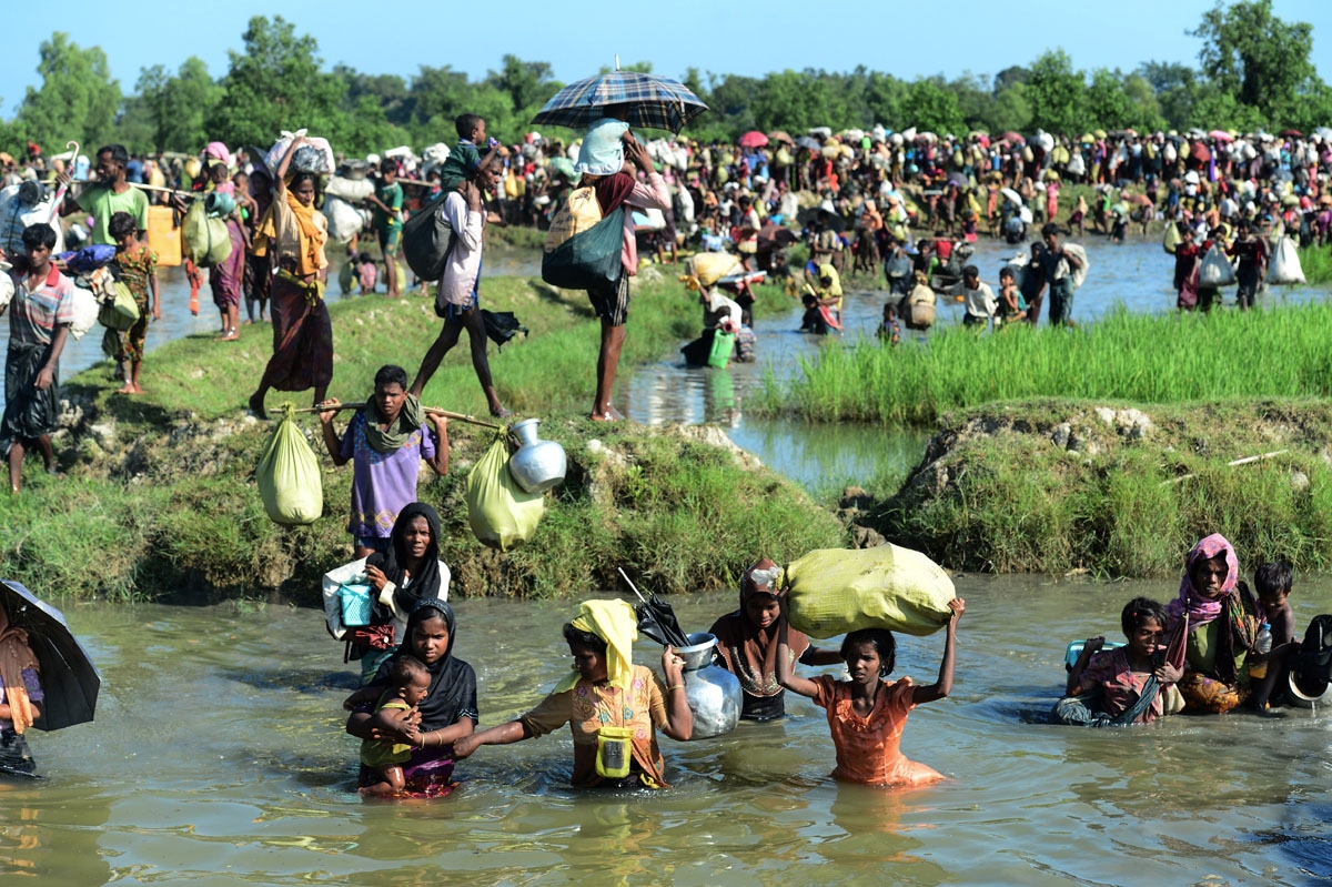 Rohingya refugees walk through a shallow canal after crossing the Naf River as they flee violence in Myanmar to reach Bangladesh in Palongkhali near Ukhia on October 16, 2017.