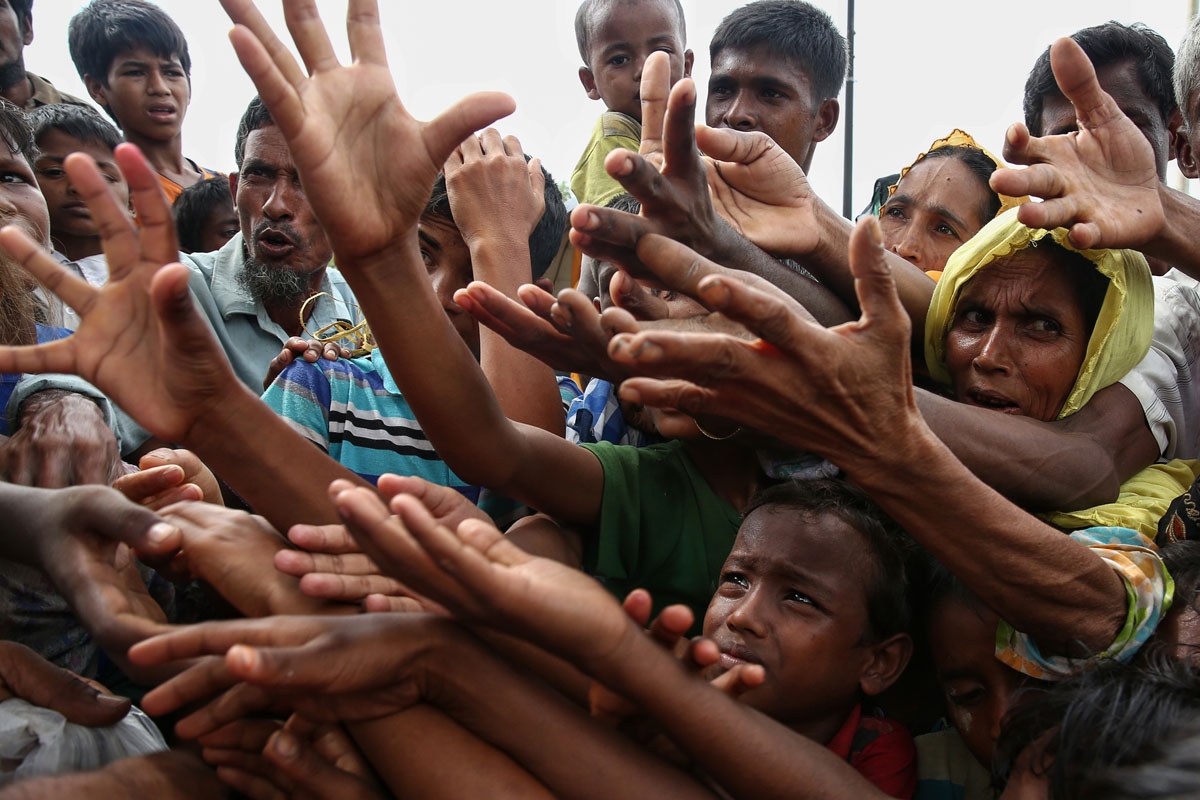 Rohingya refugees reach for food aid at the Kutupalong refugee camp in Ukhiya near the Bangladesh-Myanmar border.