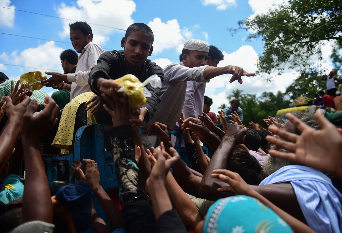 Rohingya refugees from Myanmar gather around a truck delivering food aid in Ukhia on September 14, 2017. 