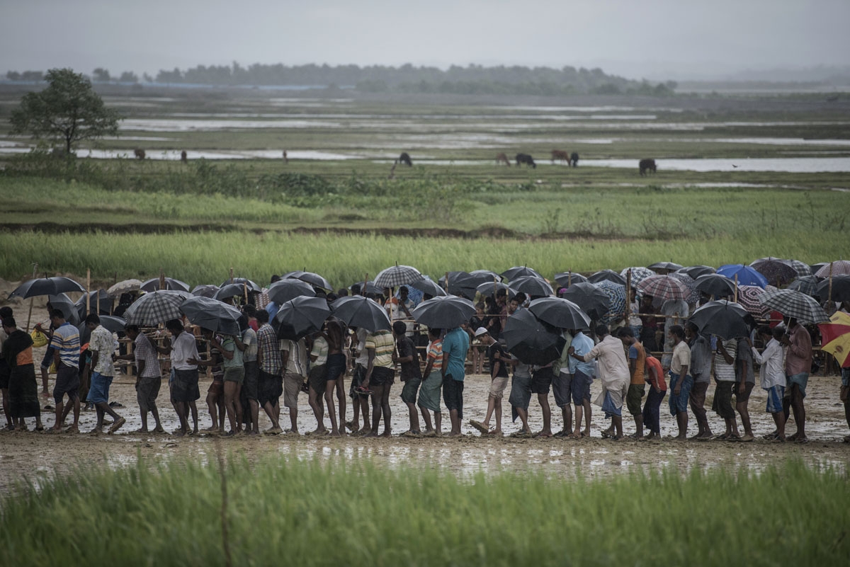 Rohingya Muslim refugees wait in line under the rain during a food distribution under at Nayapara refugee camp in Bangladesh's Ukhia district on October 6, 2017.