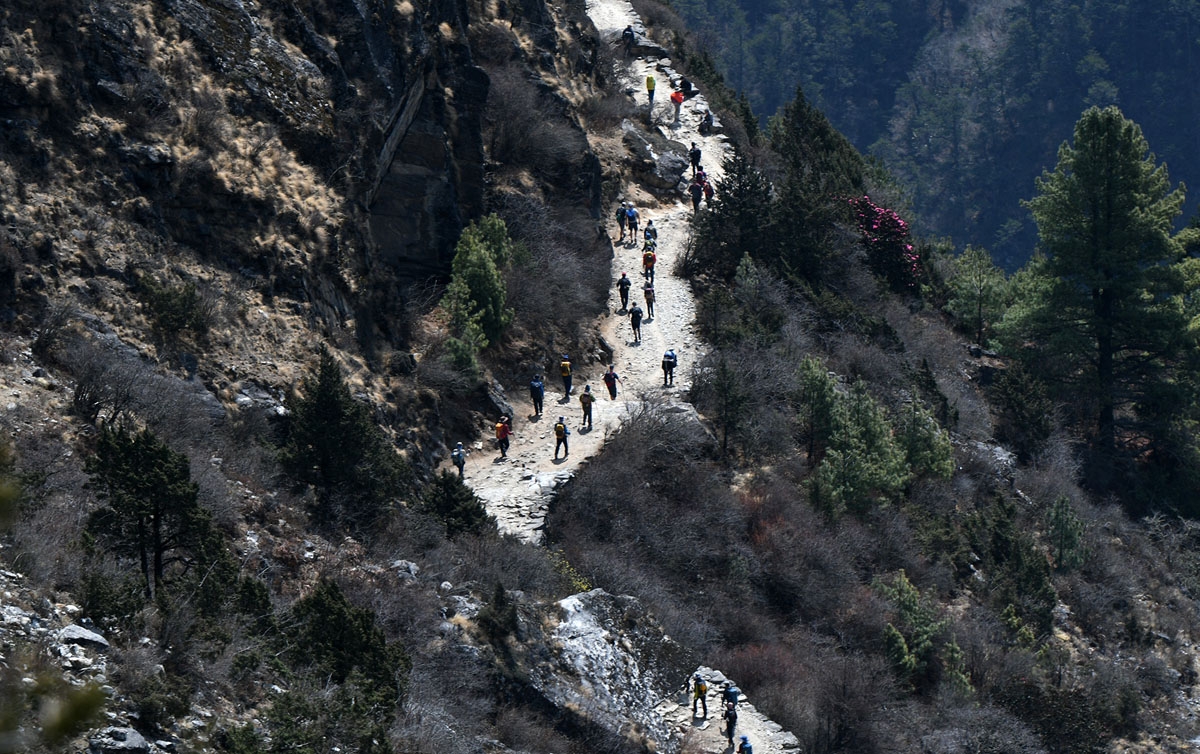 Trekkers and porters walk along a path in the Everest region, April 17, 2018.