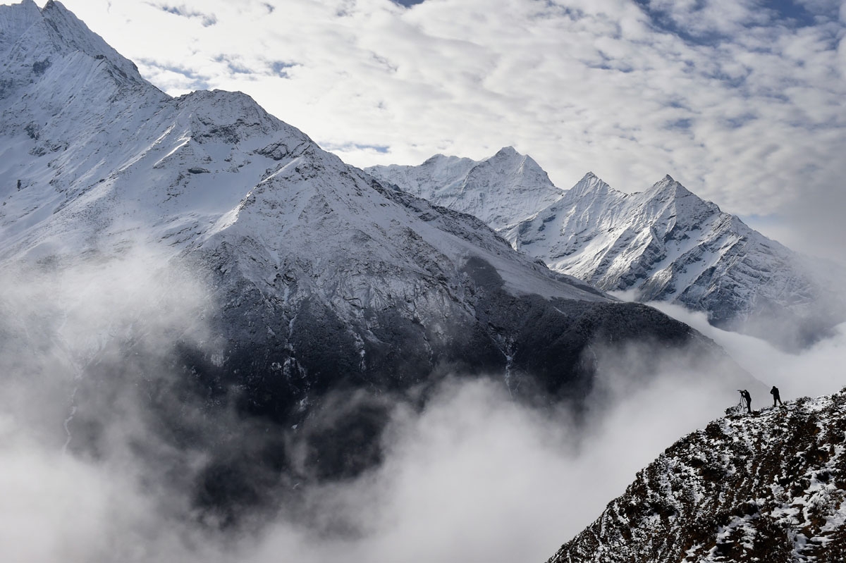 Agence France-Presse reporter Ammu Kannampilly (2R), and Nepalese guide Pasang Sherpa (R) stand on a ridge over a valley leading north into the Khumbu region as they try to get a clear view of Mt. Everest on April 18, 2015.