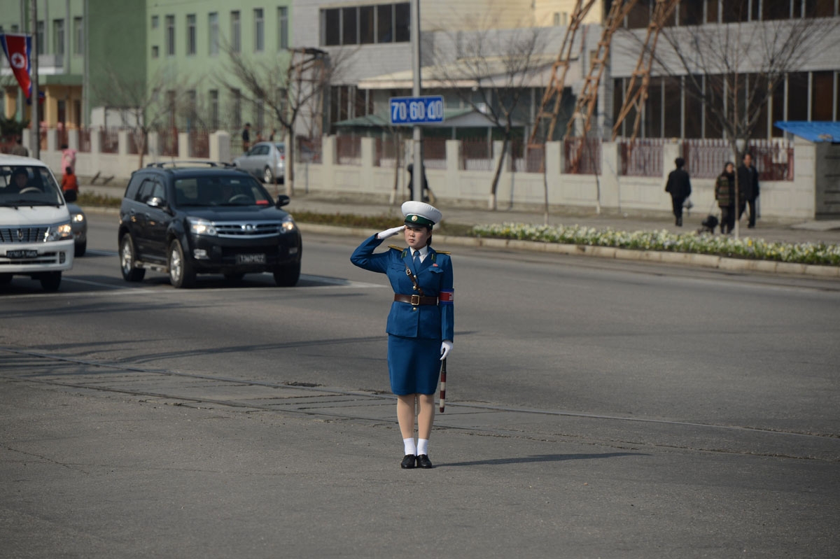 A transit controler salutes as a bus with journalists drives by in Pyongyang on April 11, 2012