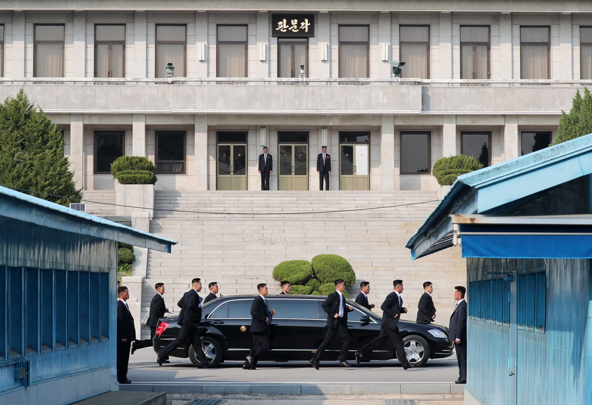North Korean bodyguards jog next to a car carrying North Korea's leader Kim Jong Un returning from the North after a lunch break during the inter-Korean summit at the truce village of Panmunjom on April 27, 2018.