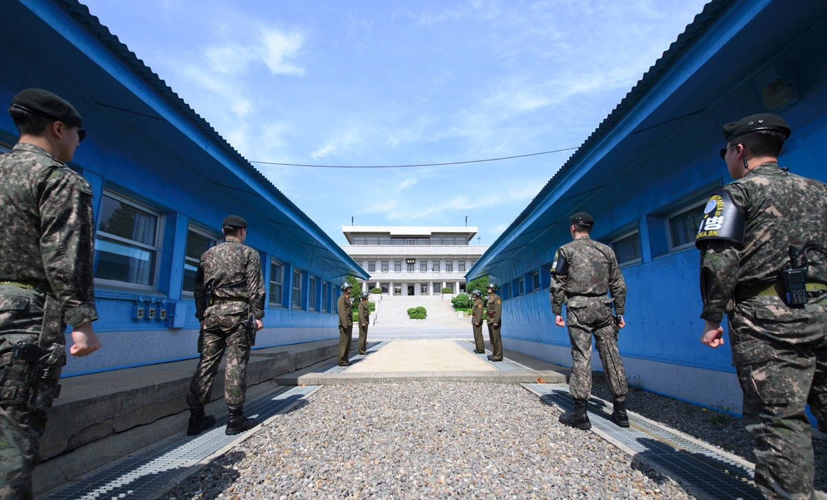 South Korean soldiers (front) and North Korean soldiers (rear) stand guard before the military demarcation line on the each side of the truce village of Panmunjom in the Demilitarized zone (DMZ) dividing the two Koreas on April 26, 2018 ahead of the inter