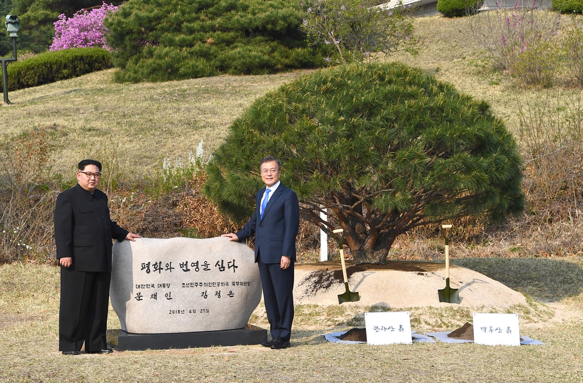 North Korea's leader Kim Jong Un (L) and South Korea's President Moon Jae-in (R) pose in front of a stone inscribed Peace and Prosperity Are Planted as they participate in a tree-planting ceremony next to the Military Demarcation Line that forms the borde
