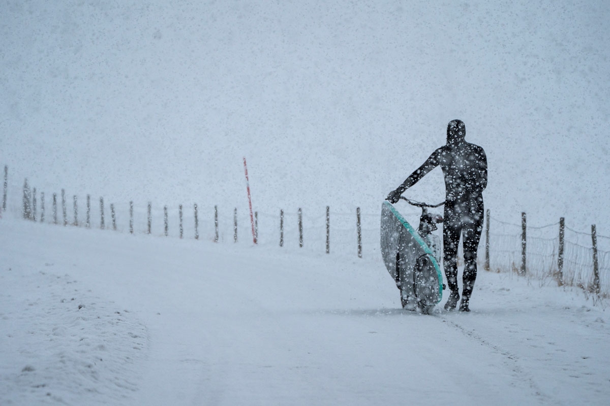 A surfer carries his surfboard on a bicycle under snowfall, on March 11, 2018, in Unstad, northern Norway, Lofoten islands, within the Arctic Circle as air temperature drops minus 13°C and water temperature above 4°C