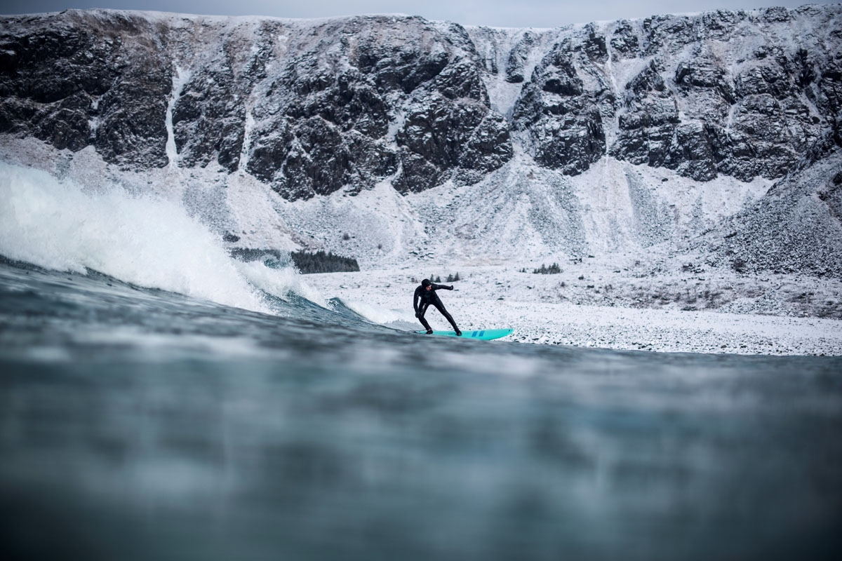 A surfer rides a wave on March 10, 2018 in Unstad, northern Norway, Lofoten islands, within the Arctic Circle as air temperature drops minus 13°C and water temperature above 4°C.