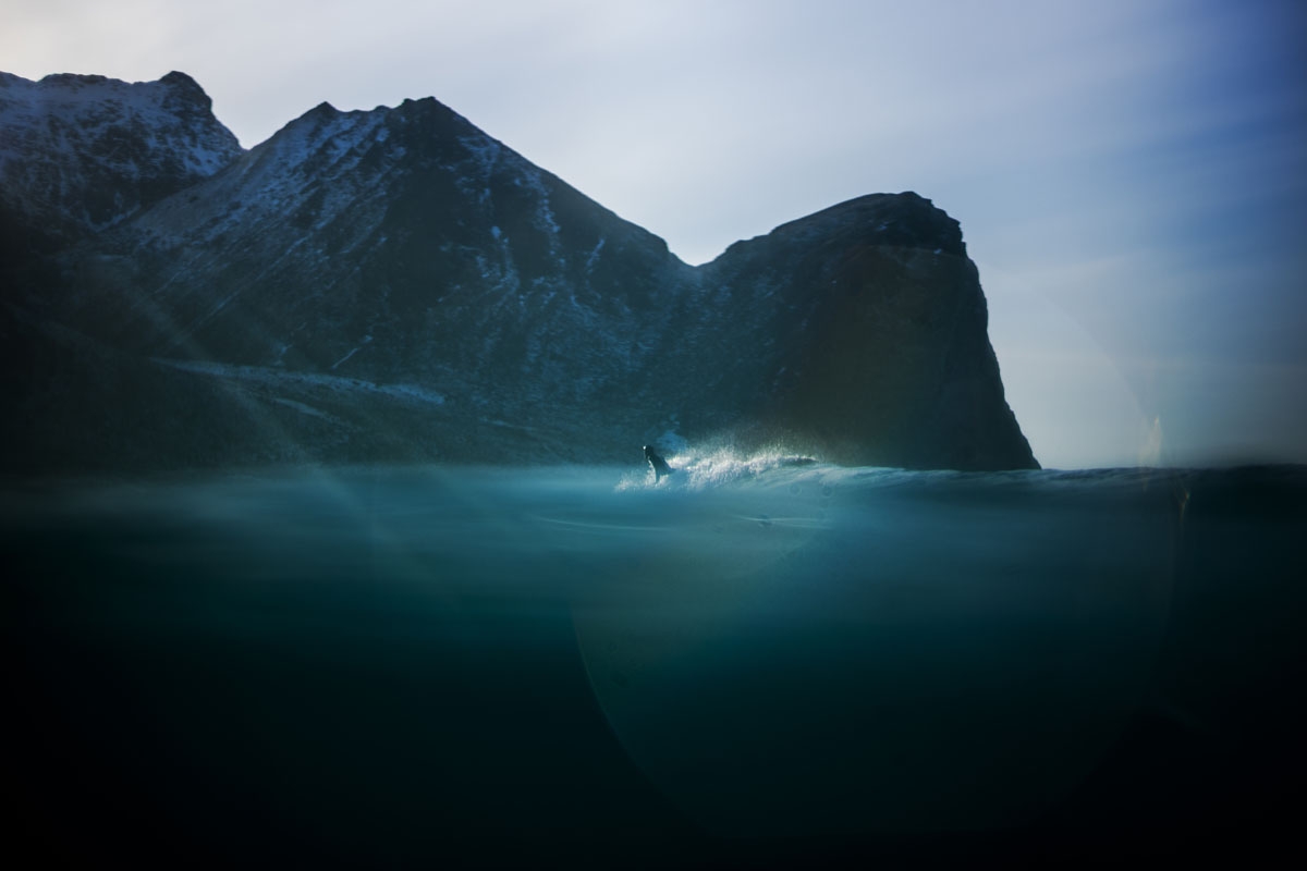 A surfer rides a wave on March 10, 2018 in Unstad, northern Norway, Lofoten islands, within the Arctic Circle as air temperature drops minus 13°C and water temperature above 4°C