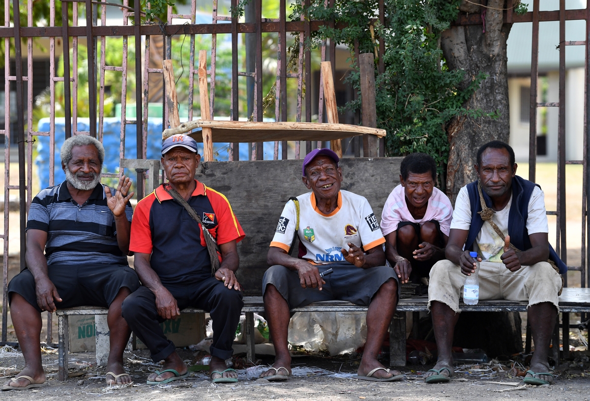 Papuan villagers sit outside a women's only makeshift market on the outskirts of Port Moresby on November 19, 2018, one day after the Asia-Pacific Economic Cooperation (APEC) Summit.
