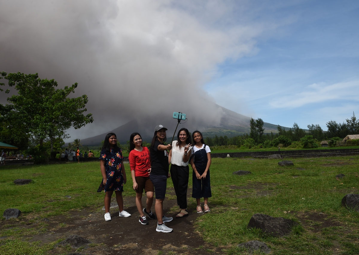 Local tourists take selfie as Mayon volcano spews ash at Cagsawa ruins in Daraga town, Albay province, south of Manila on January 30, 2018.