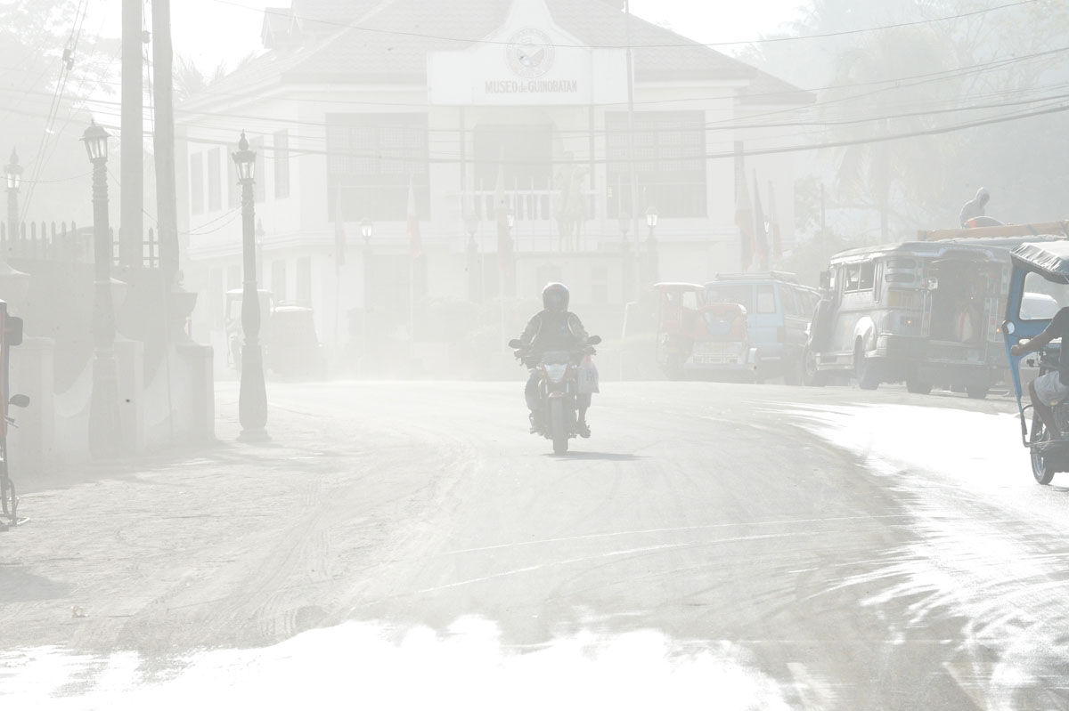 A motorist covering is face from ash traverses a road as Mayon volcano spews ash in Guinobatan town, Albay province, south of Manila on January 30, 2018.