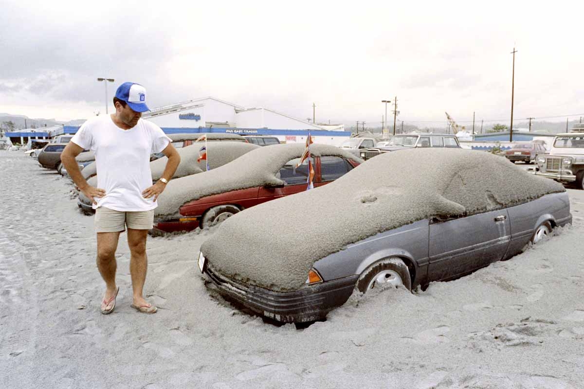 A US Navy personnel looks at his volcanic ash covered car at the Subic Naval Base parking lot, on June 19, 1991