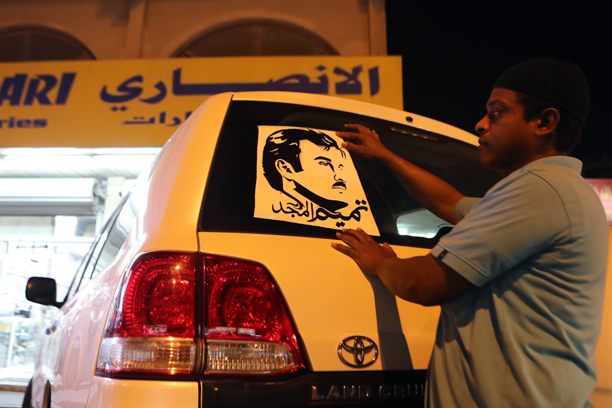 A man puts on a car a sticker portraying Qatar's Emir Sheikh Tamim bin Hamad Al-Thani outside a shop in the capital Doha on June 11, 2017.