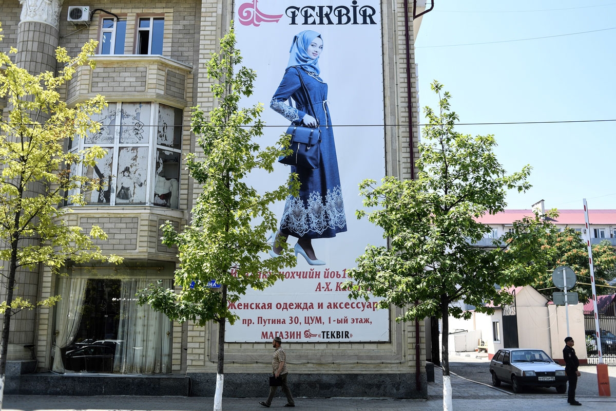 A man walks past a banner showing a woman dressed in Islamic clothes on an avenue named after Russian President Vladimir Putin in central Grozny on July 26, 2017.