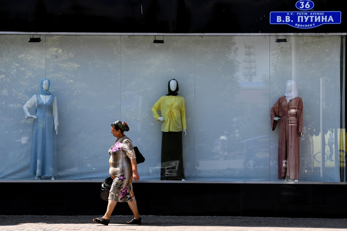 A woman walks past a shop selling Islamic clothes for women on an avenue named after Russian President Vladimir Putin in central Grozny on July 26, 2017.
