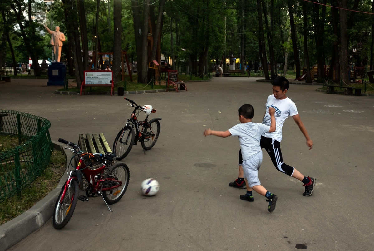 Boys play football next to a statue of Vladimir Lenin, the founder of the Soviet Union, in a park in Nizhny Novgorod on July 1, 2018. /