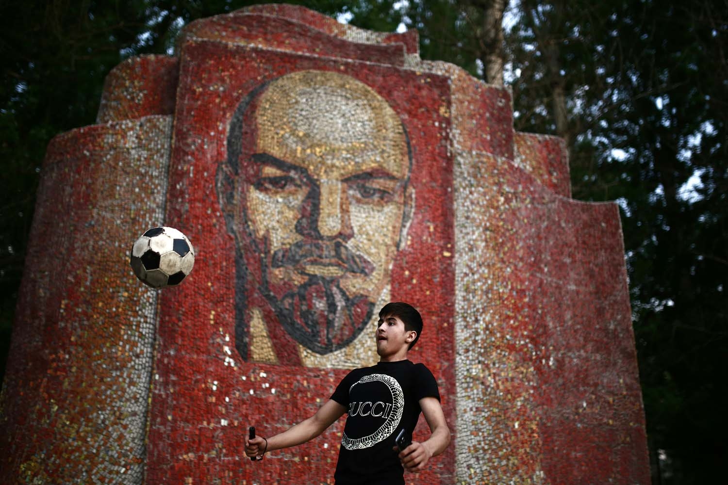 A boy juggles with a ball in front of a mosaic depicting Russian communist leader Vladimir Lenin, on June 26, 2018 in Kazan during the Russia 2018 World Cup football tournament.