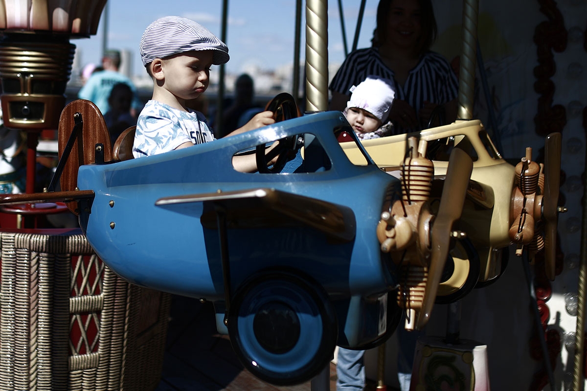 A boy rides a plane in a carousel in Kazan on June 17, 2018 during the Russia 2018 World Cup football tournament. Kazan is one of Russia's oldest cities but boasts a vibrant youth culture being home to 30 of Russiaâs largest universities. Kazan is one