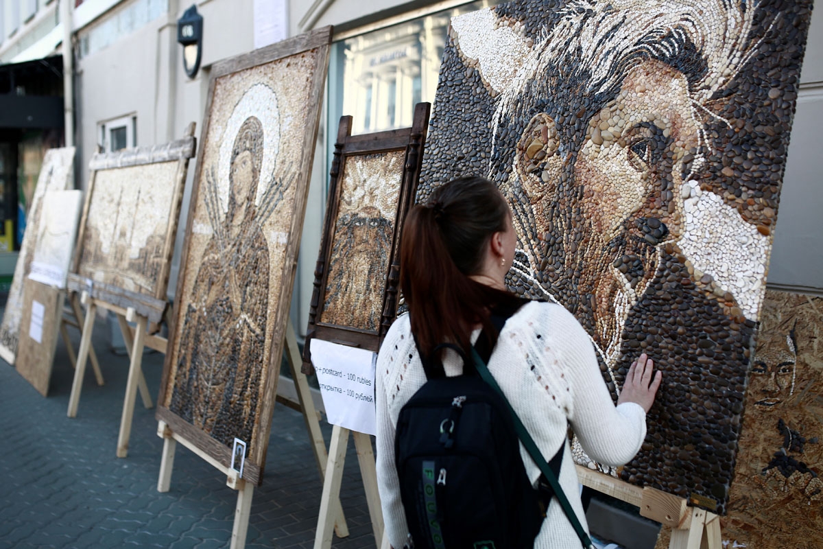 A woman touches an artwork made of stones and shells depicting Argentinian's forward Lionel Messi in Kazan on June 17, 2018 during the Russia 2018 World Cup football tournament. / A