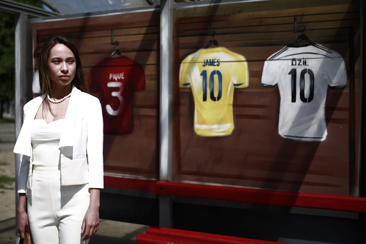 A woman waits at a bus stop with football jerseys painted on it in Kazan on June 22, 2018