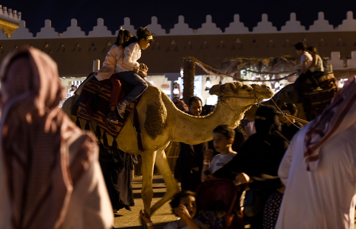 Saudi children ride a camel at Al-Qasim pavilion, during the 32nd Janadriyah Culture and Heritage Festival, held on the outskirts of the capital Riyadh on February 17, 2018. / AFP PHOTO / Fayez Nureldine