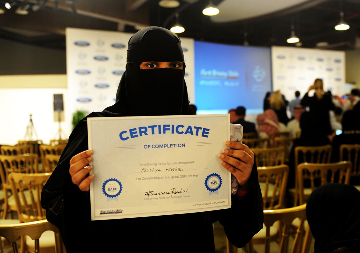 A Saudi woman poses for a photo with a certificate after completing a driving course in Jeddah on March 7, 2018.