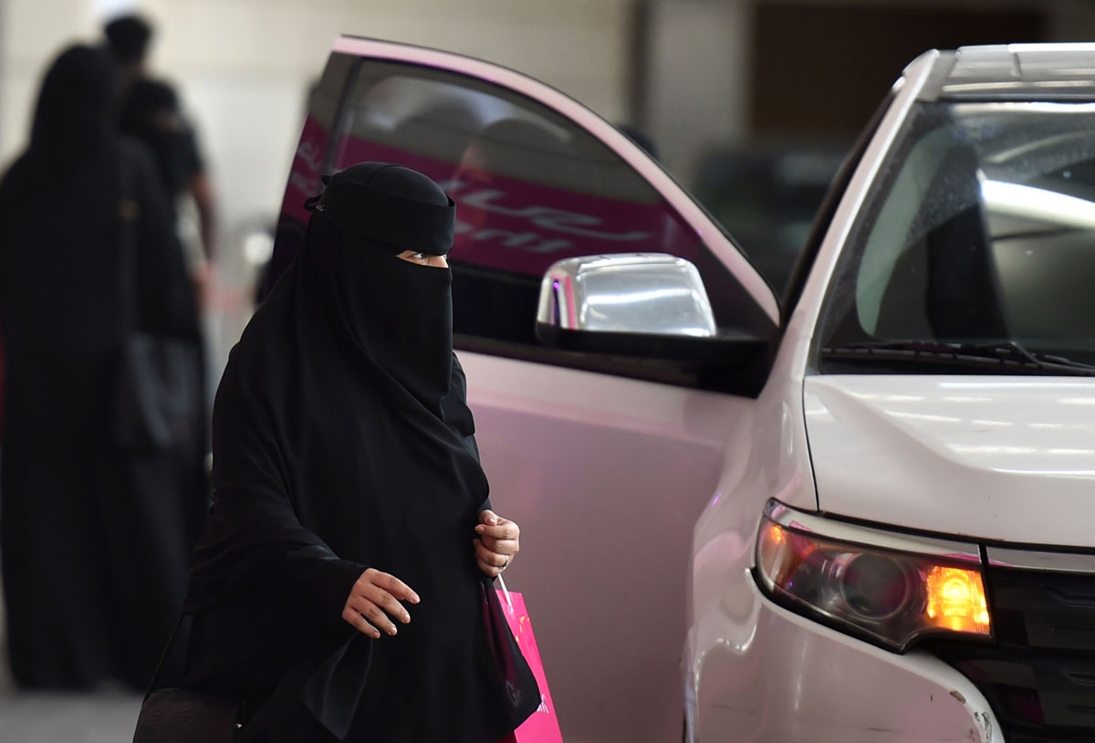 A Saudi woman walks past a car outside a hotel in the Saudi capital Riyadh, on September 28, 2017.