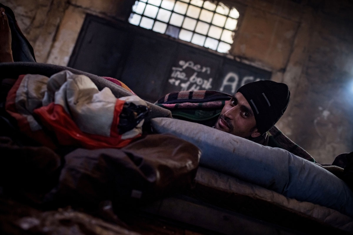 A migrant sits in a makeshift shelter at an abandoned warehouse in Belgrade on December 8, 2016.
