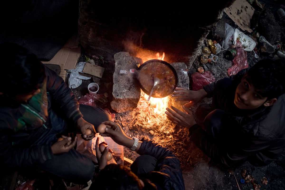 Migrants prepare a meal at a makeshift shelter at an abandoned warehouse in Belgrade on December 8, 2016.