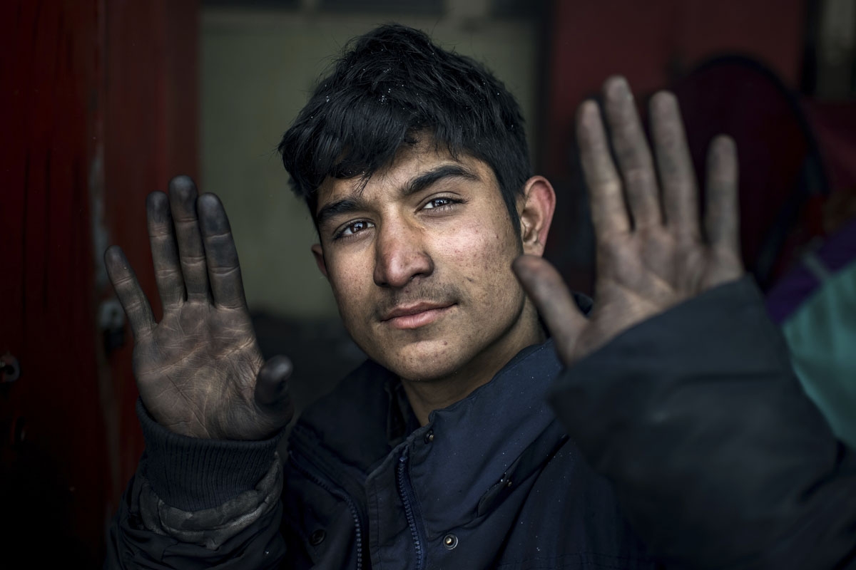 A migrant shows his hands while eating a meal provided by volunteers, outside of derelict warehouses used as a makeshift shelter, in Belgrade on January 11, 2017, as temperatures drop to -15 degrees Celsius in the evening.