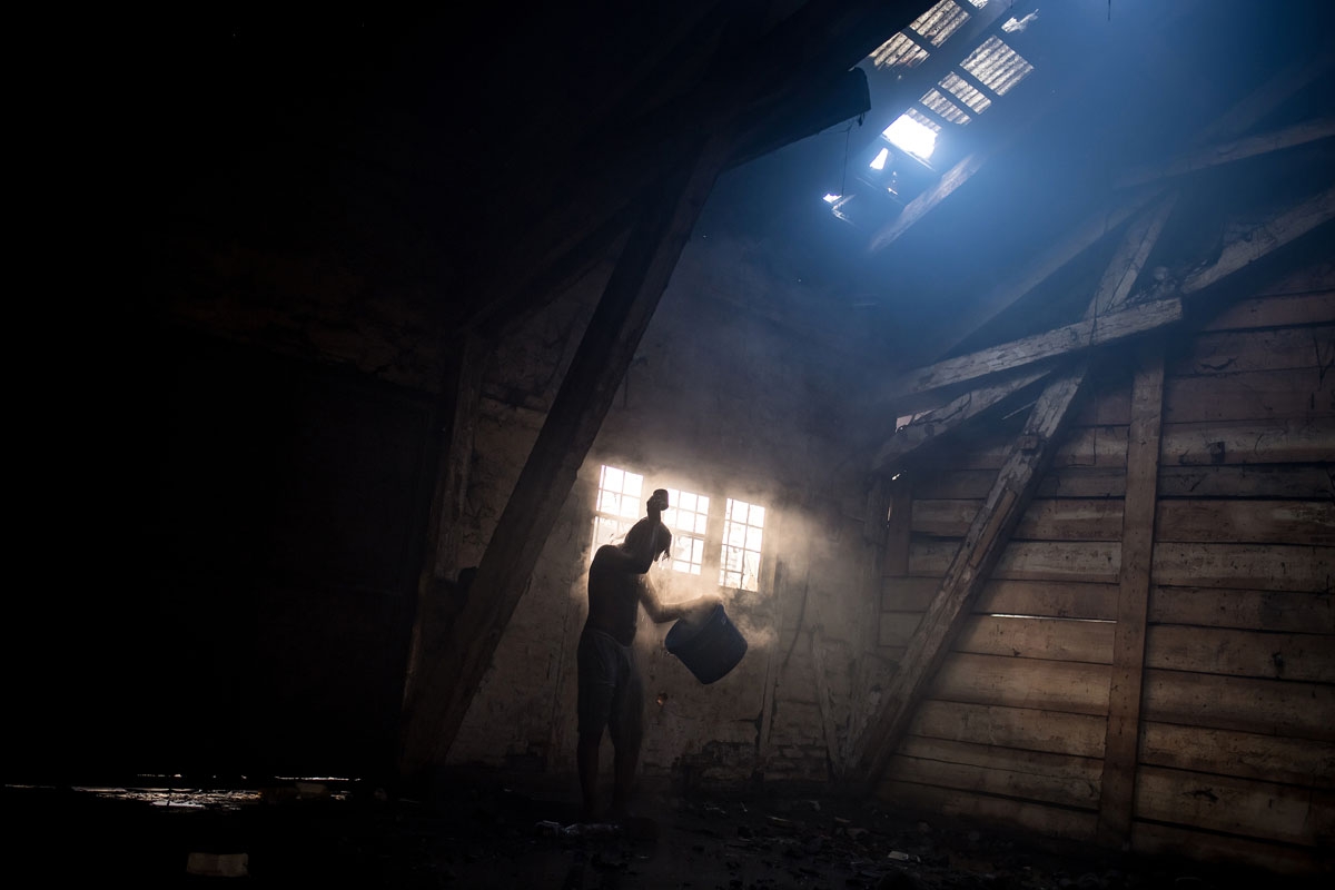 A migrant washes himself inside a derelict warehouse used as a makeshift shelter in Belgrade on January 15, 2017, with temperatures just bellow zero Celsius overnight.