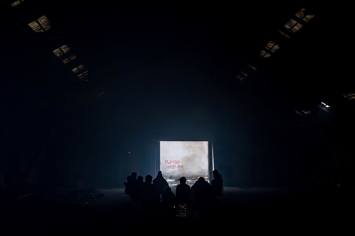 Migrants gather around a bonfire inside of derelict warehouse used as a shelter near Belgrade's main railway station on January 17, 2017, with temperatures bellow zero Celsius.