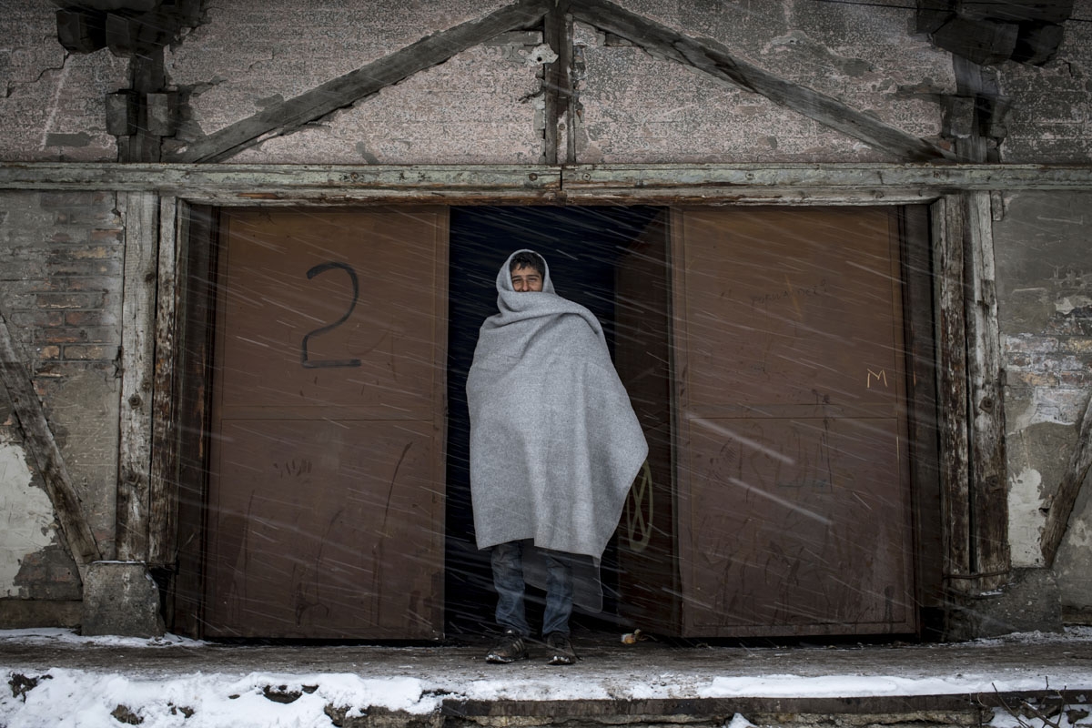 A migrant walks out of a makeshift shelter at an abandoned warehouse in Belgrade on January 11, 2017, as temperatures dropped to -15 degrees Celsius overnight.