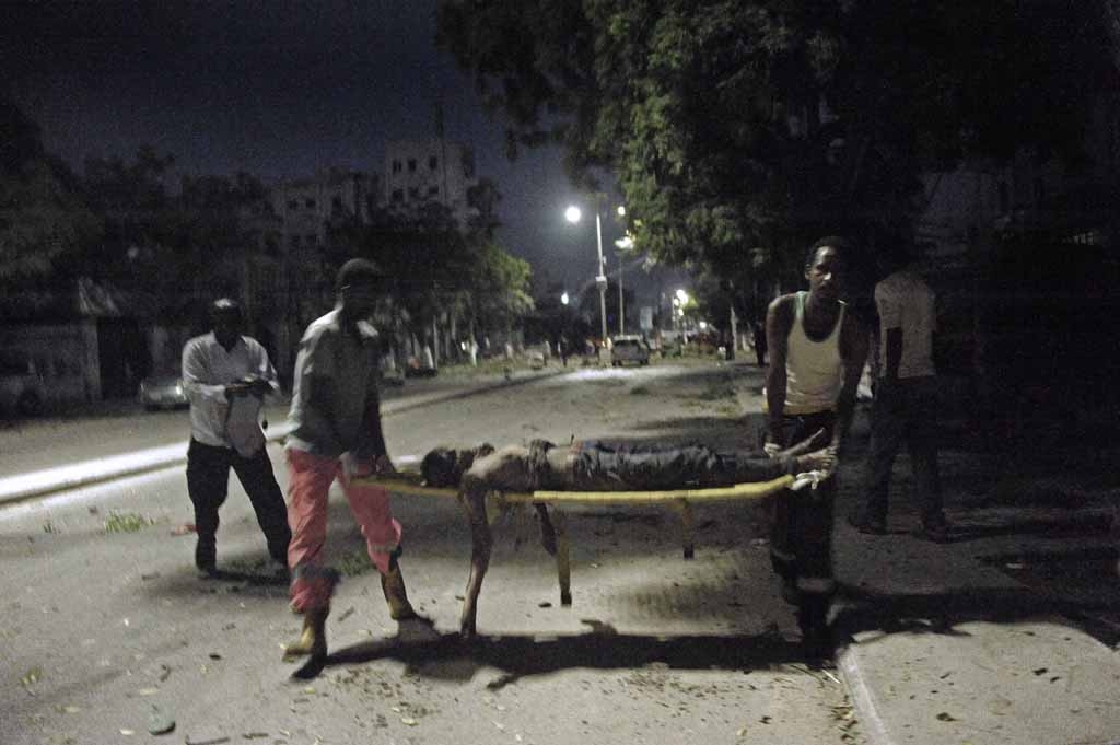 People carry a victim of a terror attack at the Ambassador Hotel, after Somalia's Al-Qaeda-linked Shabaab on June 1, 2016, launched a deadly attack on a top Mogadishu hotel popular with MPs, setting off a car bomb and fighting security forces inside the People carry a victim of a terror attack at the Ambassador Hotel, after Somalia's Al-Qaeda-linked Shabaab on June 1, 2016, launched a deadly attack on a top Mogadishu hotel popular with MPs, setting off a car bomb and fighting security forces inside the