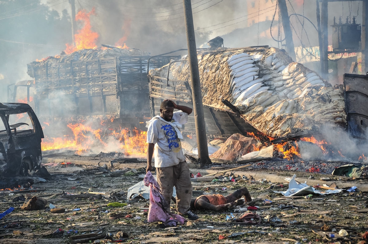 A Somali man reacts next to a dead body on the site where a car bomb exploded at the center of Mogadishu, on October 14, 2017.
