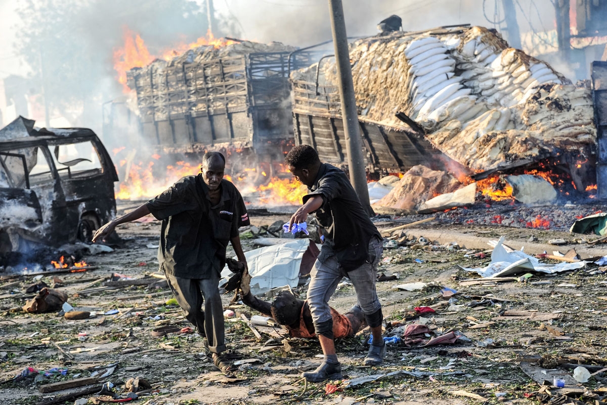 Two men carry the body of a victim following the explosion of a truck bomb in the centre of Mogadishu, on October 14, 2017.