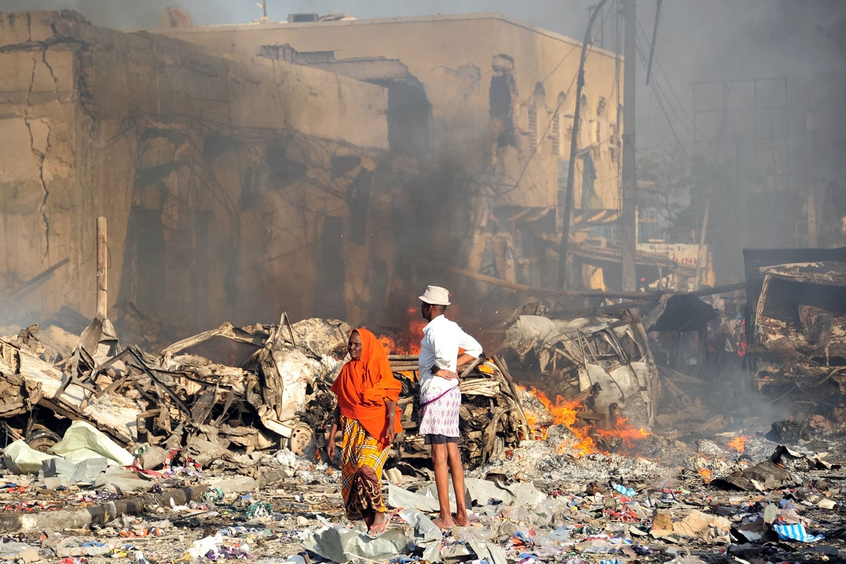 A man and woman look at the damages on the site of the explosion of a truck bomb in the centre of Mogadishu, on October 14, 2017.