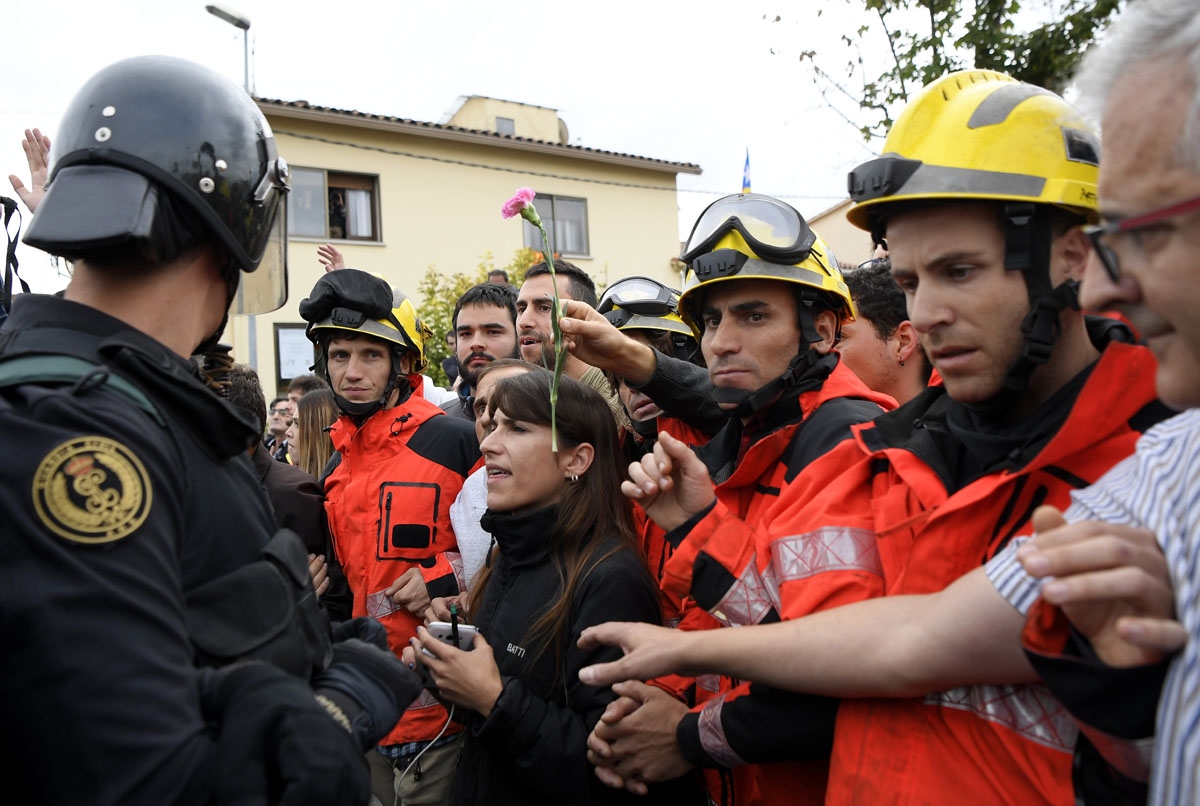 Firemen try to hold a group of people in front of Spanish Guardia Civil officers outside a polling station in San Julia de Ramis, on October 1, 2017, on the day of a referendum on independence for Catalonia banned by Madrid.