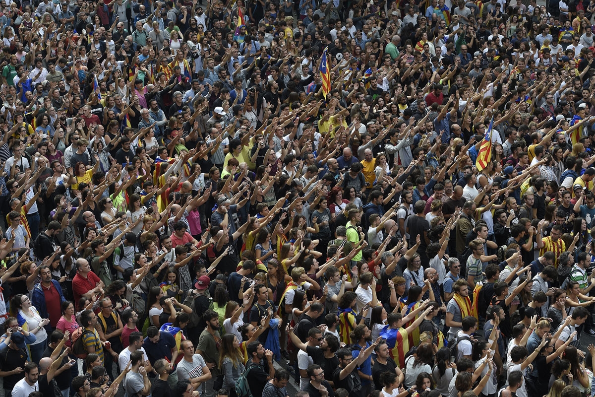 Protesters raise their hands during a protest outside the Spanish police headquarters in Barcelona as part of a general strike in Catalonia called by Catalan unions on October 3, 2017.