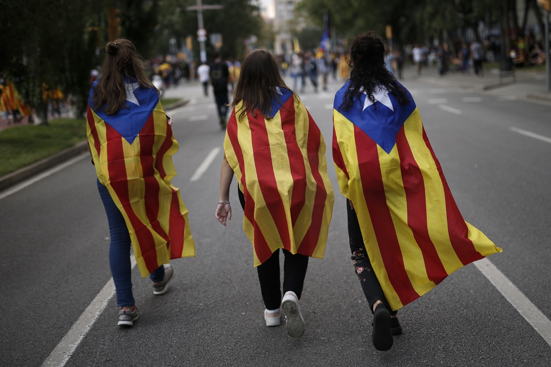 Three girls walk as they sport Esteladas (Pro-independence Catalan flags) during a pro-referendum demonstration on September 28, 2017 in Barcelona.