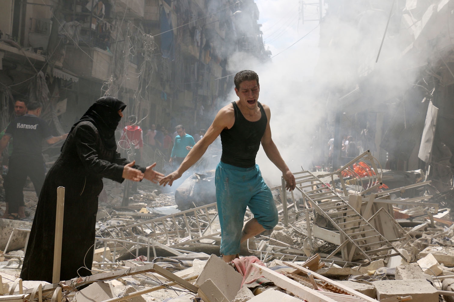 People walk amid the rubble of destroyed buildings following a reported air strike on the rebel-held neighbourhood of al-Kalasa in the northern Syrian city of Aleppo, on April 28, 2016