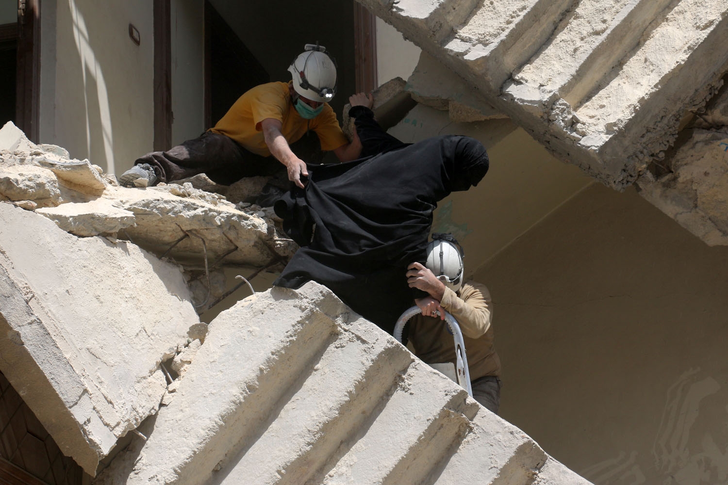 Syrian civil defence volunteers evacuate a woman from a destroyed building following a reported air strike on the rebel-held neighbourhood of al-Kalasa in the northern Syrian city of Aleppo, on April 28, 2016