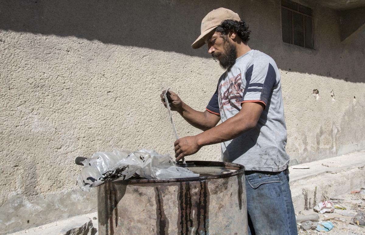 Abu Ahmed, a 40-year-old Syrian man, fills a barrel with plastic as part of a refining process to produce fuel on September 10, 2016, in Aleppo's rebel-held eastern district of Sakhur.