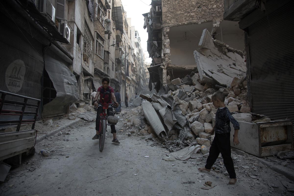 Syrians walk through the rubble following an air strike in Aleppo's rebel-controlled neighbourhood of Karm al-Jabal on September 18, 2016.