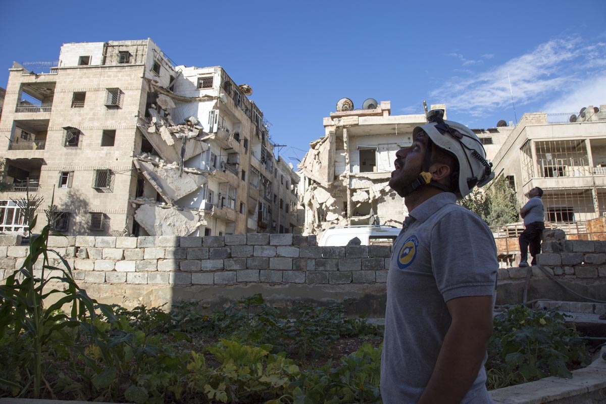 A Syrian rescuer looks towards the sky following an air strike in the rebel-held Ansari district in the northern Syrian city of Aleppo on September 23, 2016
