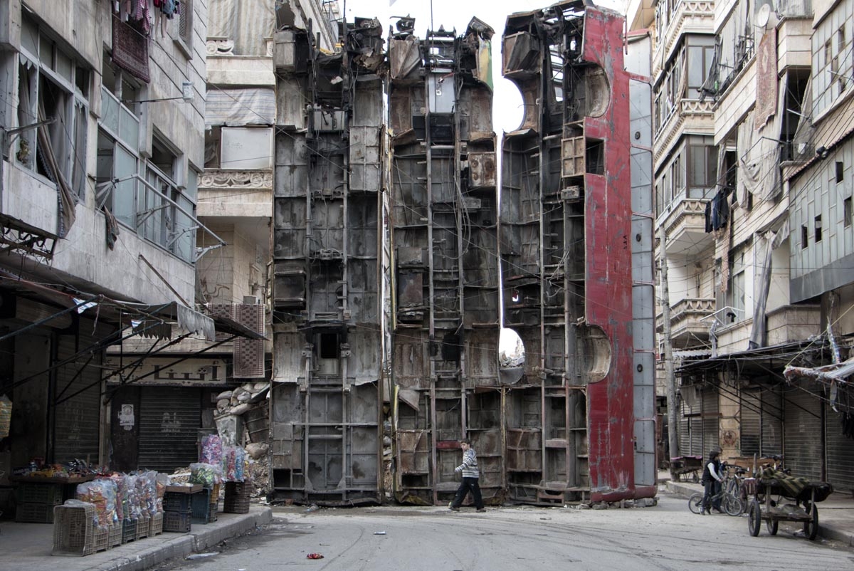 A young boy walks past a makeshift barricade made of wreckages of buses to obstruct the view of regime snipers and to keep people safe, on March 14, 2015 in the rebel-held side of the northern Syrian city of Aleppo. Syria's conflict enters its fifth year