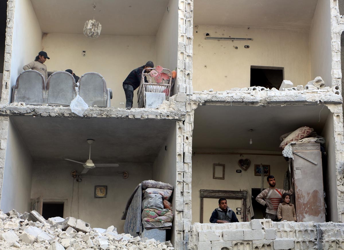 Civilians photographed in a damaged building in Syria's northern city of Aleppo following a reported air strike by government forces on December 7, 2015.
