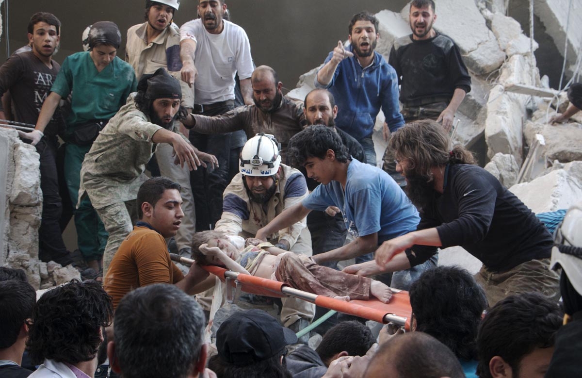Syrian rescue workers and citizens carry a child on a stretcher from a building following a reported barrel bomb attack by Syrian government forces at the Al-Firdaws neighbourhood of the northern Syrian city of Aleppo, on May 30, 2015